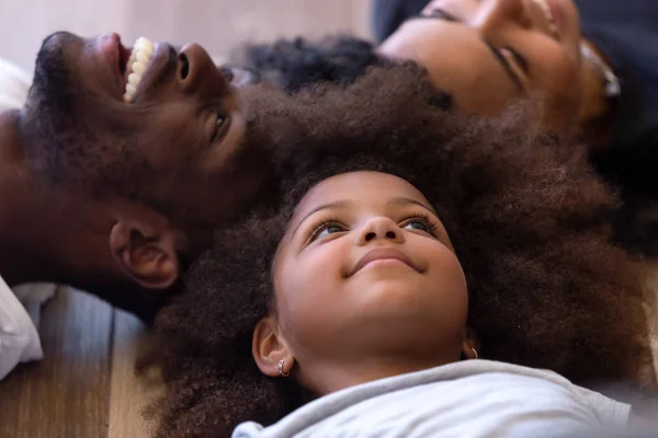 Close-up gelukkig Afro-Amerikaanse familie liggend op warme vloer samen — Stockfoto