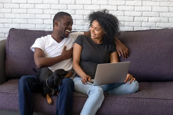 Riendo pareja afroamericana usando el ordenador portátil juntos en casa —  Fotos de Stock