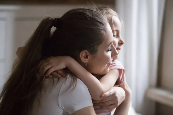 La mère aimante donne un câlin fort à sa fille les yeux fermés — Photo