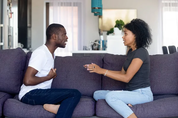 Unhappy African American couple quarreling, sitting on sofa at home — Stock Photo, Image