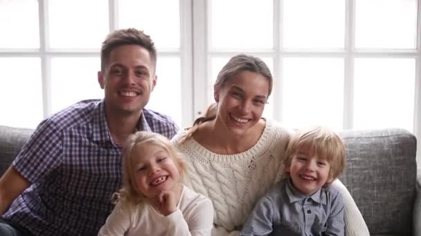 Alegre familia sonriente con dos niños riendo mirando a la cámara — Vídeos de Stock