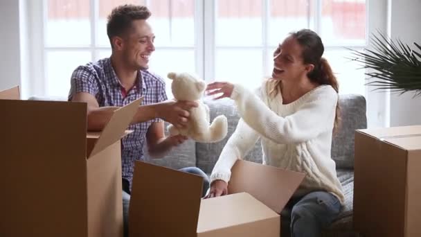 Feliz jovem casal rindo falando desempacotando caixas de papelão abertas juntos — Vídeo de Stock