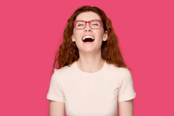 Счастливая рыжая девушка в очках смеется над шуткой — стоковое фото