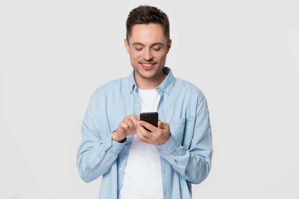 Glimlachend blanke man geïsoleerd op grijze achtergrond met behulp van smartphone — Stockfoto