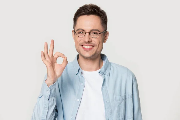 Sonriente hombre en gafas mostrar ok signo aislado en el estudio — Foto de Stock