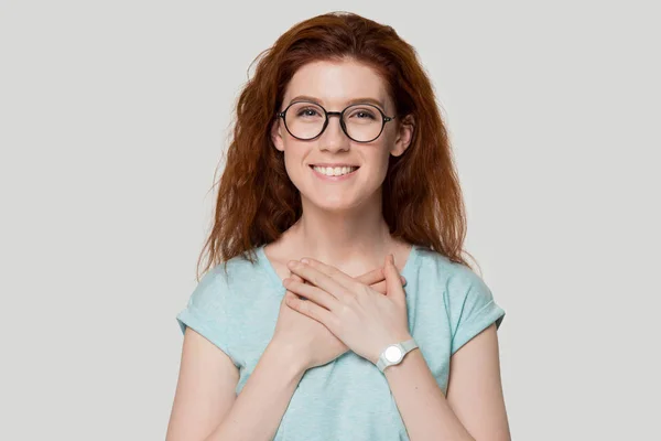 Mosolygó hálás vörös hajú lány szemüveges kezével a mellkason — Stock Fotó