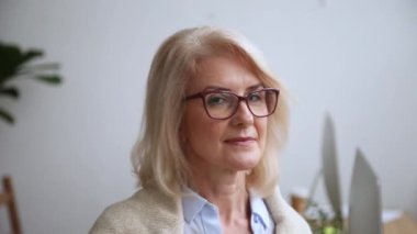 Mutlu olgun iş kadını gözlük kamera bakarak gülümseyerek