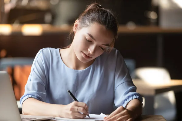 Junge fokussierte Frau sitzt am Tisch Handschrift in Notizbuch — Stockfoto