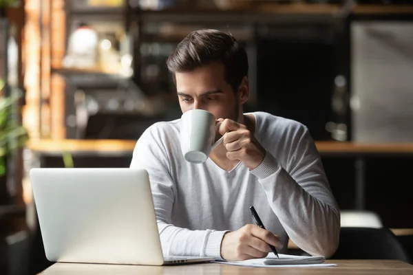 Uomo d'affari serio seduto in caffetteria a bere caffè guardando il computer — Foto Stock