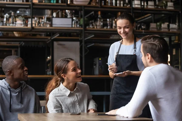 Diverse friends sitting in restaurant placing order talking with waitress — Stock Photo, Image