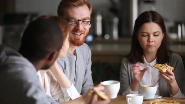 Разнообразные друзья говорят, делясь пиццей обсуждая интересные новости во время тусовки — стоковое видео