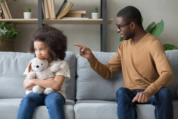 African dad scolding for discipline stubborn daughter sitting on sofa — Stock Photo, Image