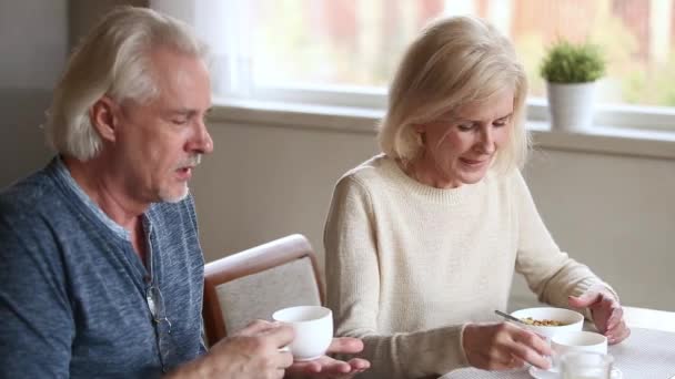 Happy middle aged couple talking eating breakfast drinking coffee together — Stock Video