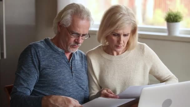 Allvarliga äldre äldre par tvistande hålla papper räkningar kontrollera finanser — Stockvideo