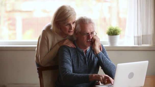 Возбужденные победители пожилой пары с помощью ноутбука переполнены онлайн победу — стоковое видео