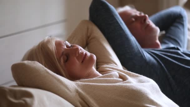 Спокойная пожилая пара среднего возраста расслабляется, опираясь на удобный диван — стоковое видео