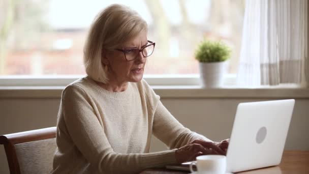 Senior vrouw met behulp van laptop gevoel ongemak opstijgen glazen — Stockvideo