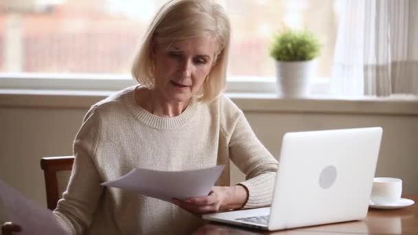 Glimlachend oud volwassen dame betalen rekeningen online op laptop — Stockvideo