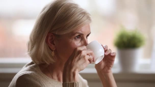 Calma feliz anciana sentada sola sosteniendo la taza disfrutando del café — Vídeos de Stock