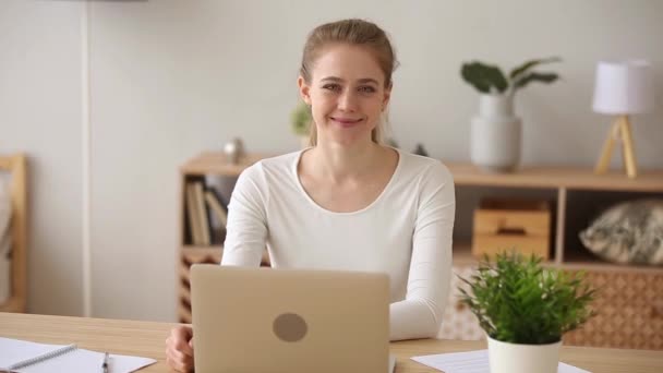 Усміхнена дівчина позує з ноутбуком для портрета, що працює з дому — стокове відео