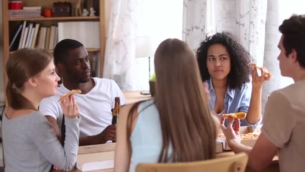 Happy multirasistiska vänner äter pizza dricka öl pratar i pizzeria — Stockvideo