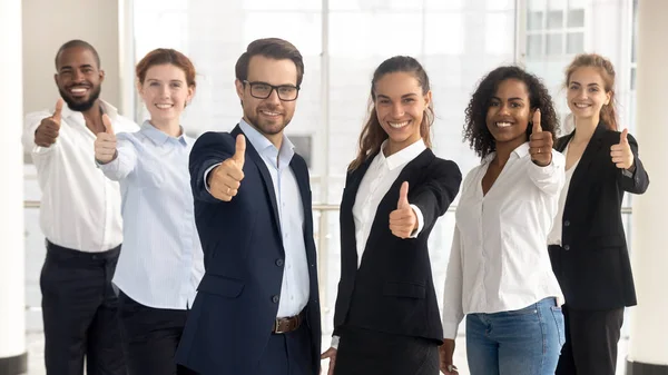 Unternehmensführer mit Mitarbeitern, die Daumen nach oben zeigen und in die Kamera schauen — Stockfoto