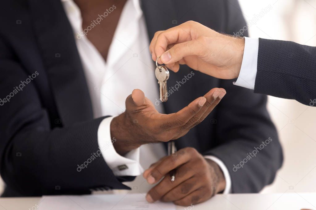 Realtor hand giving keys to african new house owner