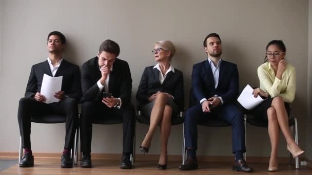 Diverse candidates for vacancy sitting on chairs waiting their turn — Stock Video