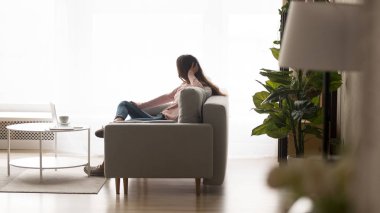 Pencereden dışarı bakan kanepede oturan pensive kadın