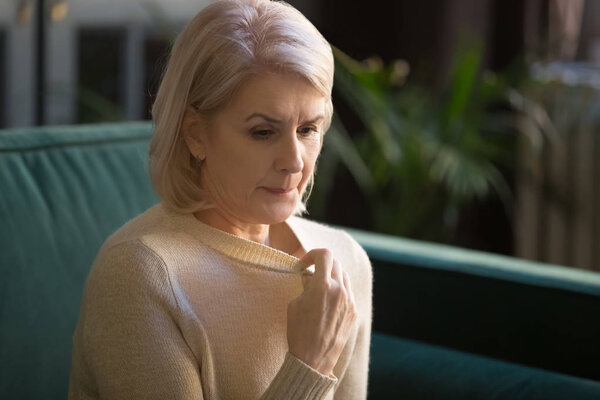 Grey haired mature woman in sweater suffering from high temperature