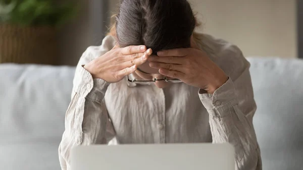 Lähikuva nainen istuu lähellä kannettavaa tuntuu stressaantunut ottaa suuria ongelmia — kuvapankkivalokuva