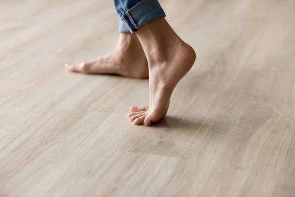 Side closeup view woman feet stands on warm wooden floor — Stock Photo, Image