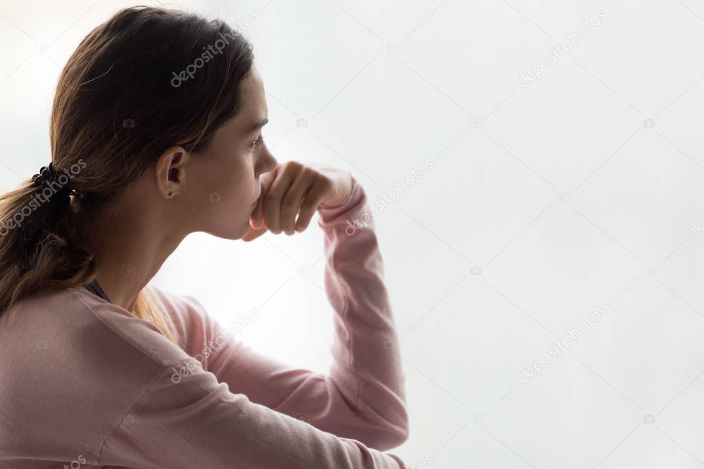 Pensive woman sitting indoors lost on thoughts side view face
