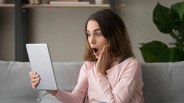 Woman looking at digital tablet screen feels shocked about news — Stock Photo, Image