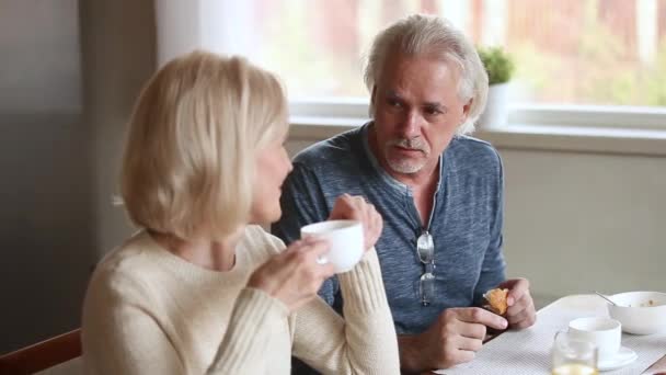 Ältere Frau und Mann plaudern lachend glücklich beim Frühstück — Stockvideo