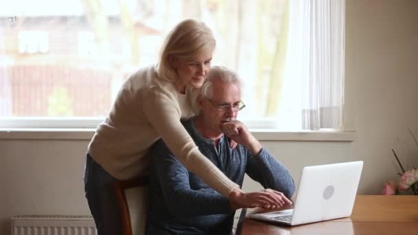 Ouderen positief paar met behulp van computer nieuwe toepassing of online bankieren — Stockvideo