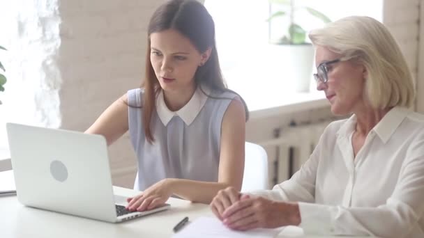 Jonge verkoopster verzekeraar consulting oude vrouwelijke klant op zoek naar laptop — Stockvideo