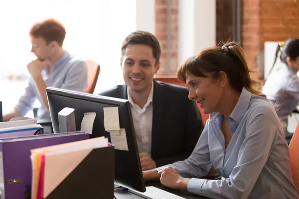 Los colegas sonrientes trabajan juntos en la PC en la oficina compartida — Foto de Stock