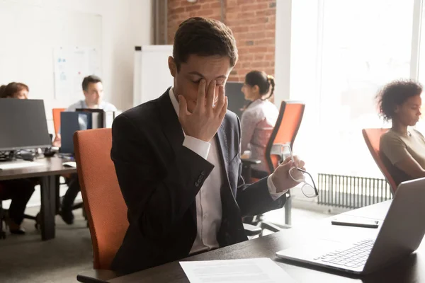 Uitgeput mannelijke werknemer massage ogen lijden aan hoofdpijn — Stockfoto