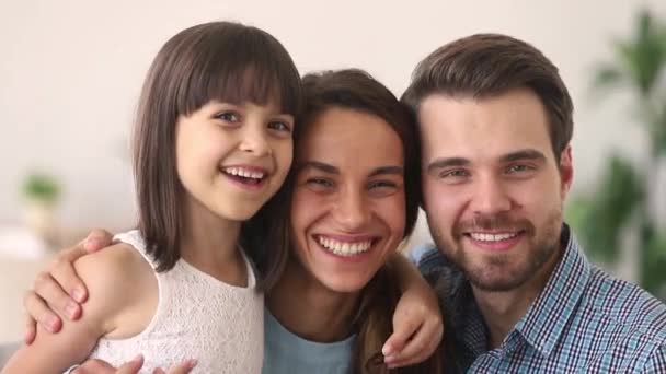 Gelukkige ouders en kind dochter omarmen lachen kijken naar camera — Stockvideo