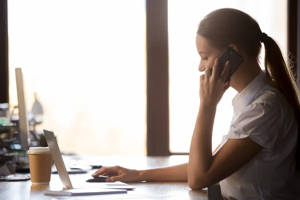 Vue latérale femme d'affaires millénaire assis au bureau parlant sur téléphone portable — Photo