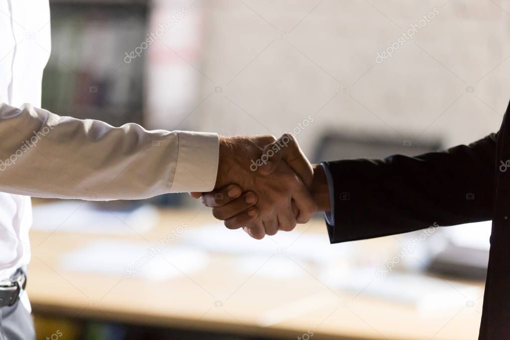 Close up diverse businessmen shaking hands at office