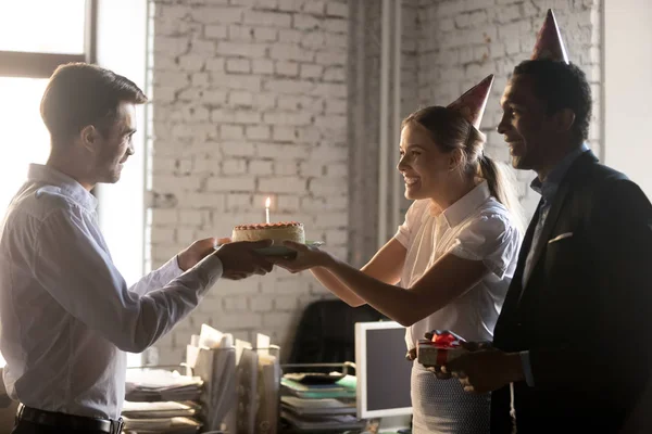 Diversos colegas felicitando a su compañero de trabajo con pastel de cumpleaños con vela — Foto de Stock