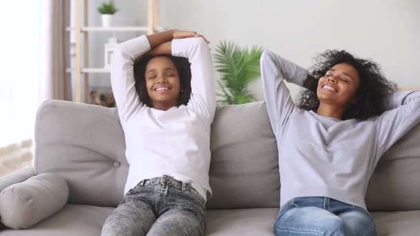 Zrelaksowany spokojny afrykański matka i córka schładzając się na kanapie — Wideo stockowe