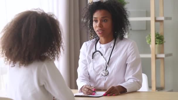 Афро-американський жіночий лікар педіатр розмовляти з пацієнтом дівчинки підлітка — стокове відео