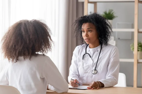 Friendly African American pediatrician doctor talking to teen girl — Stock Photo, Image