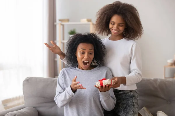 Surpreendido mãe afro-americana recebendo presente da filha adolescente — Fotografia de Stock