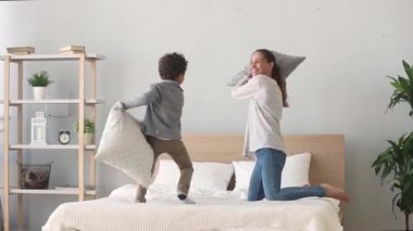 Mutlu karışık ırk anne ve oğlu yatakta yastık mücadele sahip