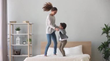 Mutlu Afrikalı çocuk çocuk ve beyaz anne yatakta atlama
