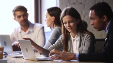 Genç beyaz kadın danışman, erkek Afrikalı Amerikalı stajyere yardım ediyor.